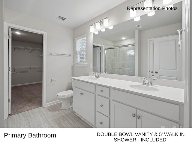 bathroom featuring a shower with door, vanity, and toilet