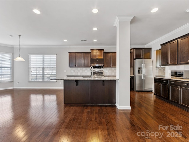 kitchen featuring light stone countertops, appliances with stainless steel finishes, crown molding, and a breakfast bar area