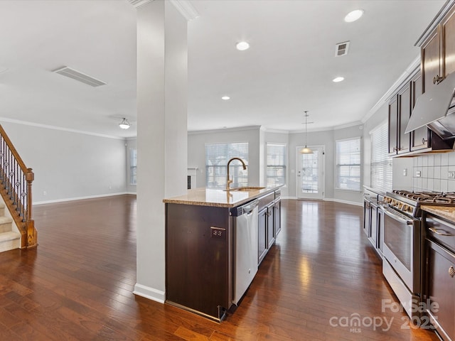 kitchen featuring dark brown cabinetry, light stone countertops, sink, an island with sink, and appliances with stainless steel finishes