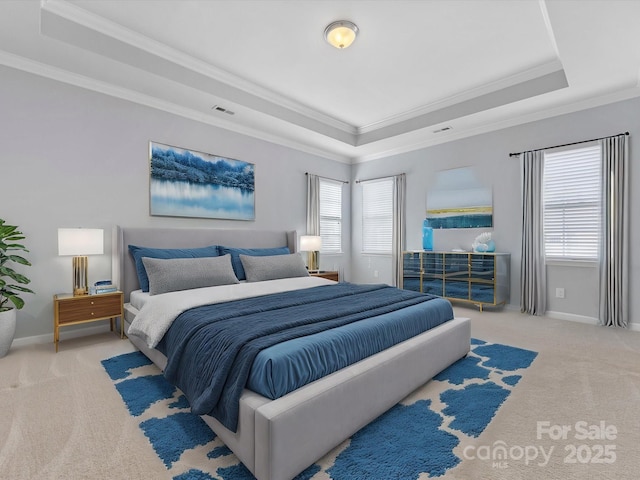 carpeted bedroom with a tray ceiling, multiple windows, and crown molding