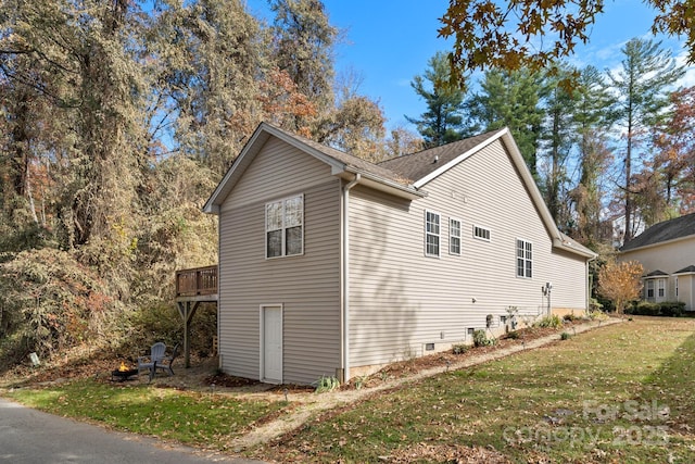 view of side of home featuring a yard and a wooden deck