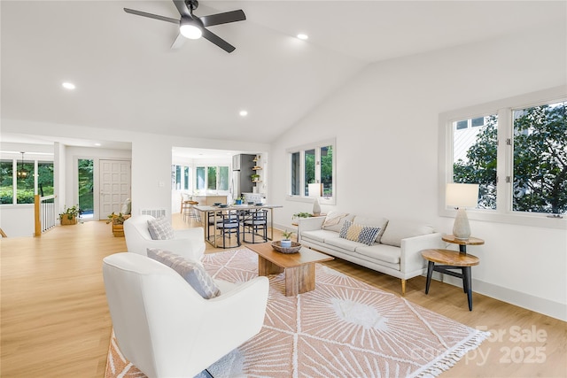 living room with light hardwood / wood-style floors, vaulted ceiling, and ceiling fan