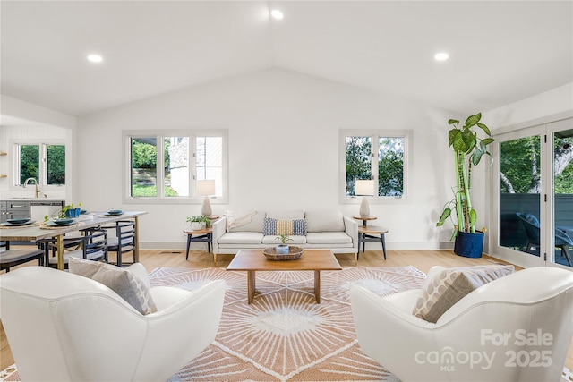 living room with lofted ceiling, sink, and light hardwood / wood-style flooring