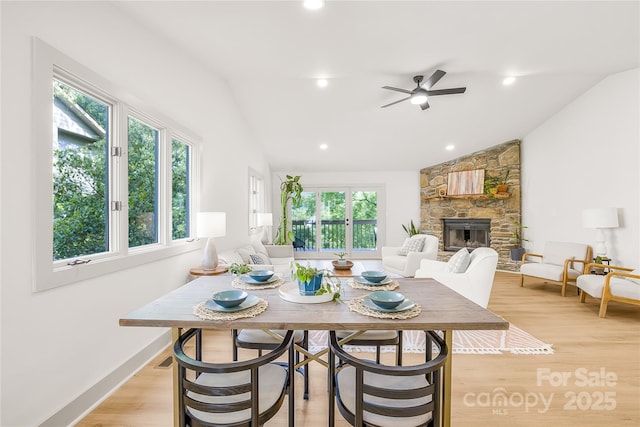 dining space featuring ceiling fan, a fireplace, light hardwood / wood-style floors, and lofted ceiling