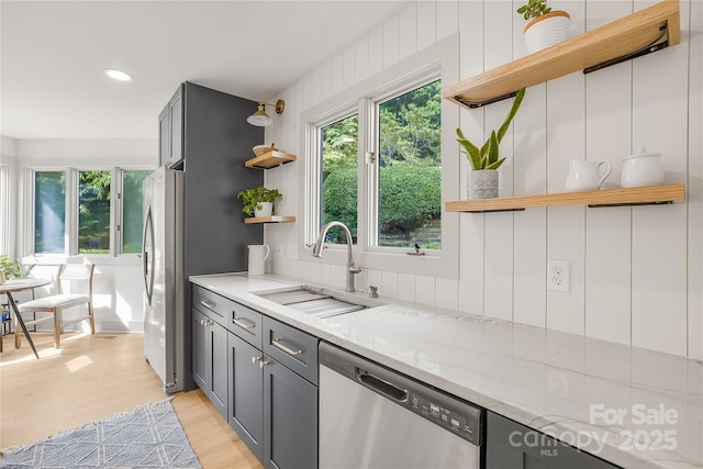 kitchen featuring sink, light stone counters, gray cabinetry, and stainless steel appliances