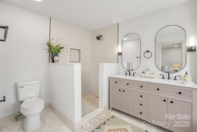 bathroom with a tile shower, vanity, and toilet