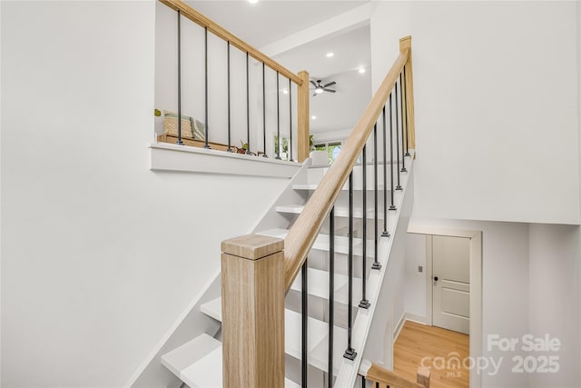 stairs featuring ceiling fan and wood-type flooring