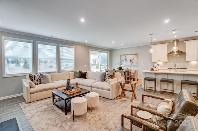 living room with recessed lighting, visible vents, baseboards, ornamental molding, and light wood-type flooring