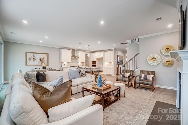 living room with light wood finished floors, baseboards, stairway, crown molding, and recessed lighting