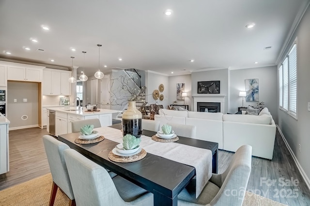 dining area with a healthy amount of sunlight, a fireplace, crown molding, and light wood-style flooring