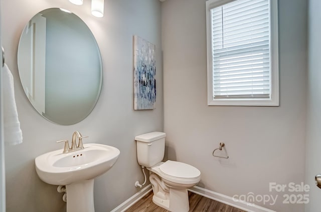 half bathroom featuring toilet, baseboards, and wood finished floors