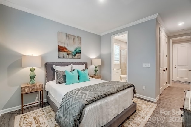 bedroom with ornamental molding, ensuite bath, wood finished floors, and baseboards