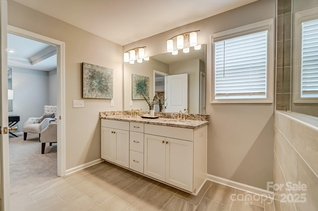 bathroom with double vanity, ensuite bath, baseboards, and a sink