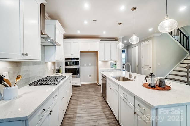 kitchen featuring a center island with sink, white cabinetry, stainless steel appliances, and a sink