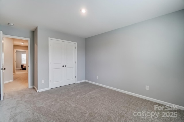 unfurnished bedroom with carpet floors, baseboards, and a closet