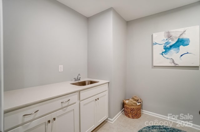 laundry area featuring light tile patterned floors, a sink, and baseboards