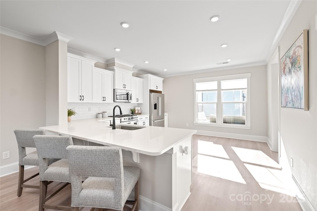 kitchen featuring sink, a kitchen bar, decorative backsplash, high end appliances, and kitchen peninsula