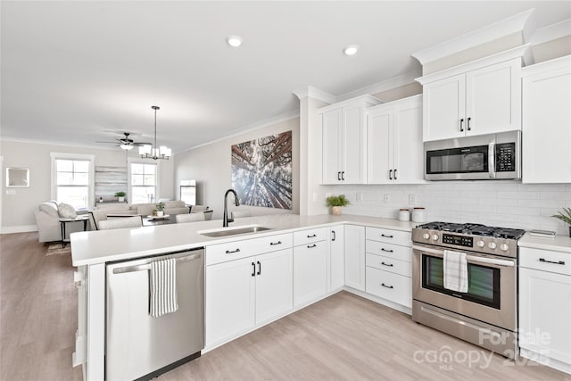 kitchen with sink, crown molding, white cabinetry, stainless steel appliances, and kitchen peninsula