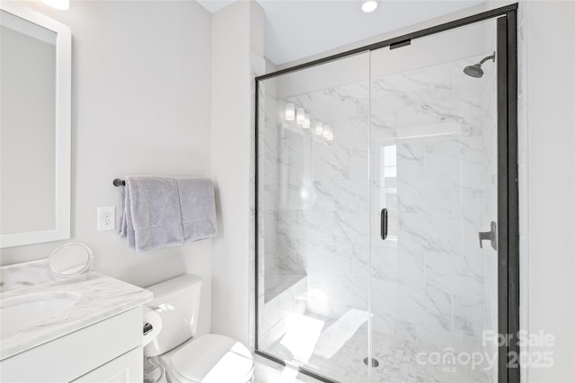 bathroom featuring vanity, a shower with shower door, and toilet