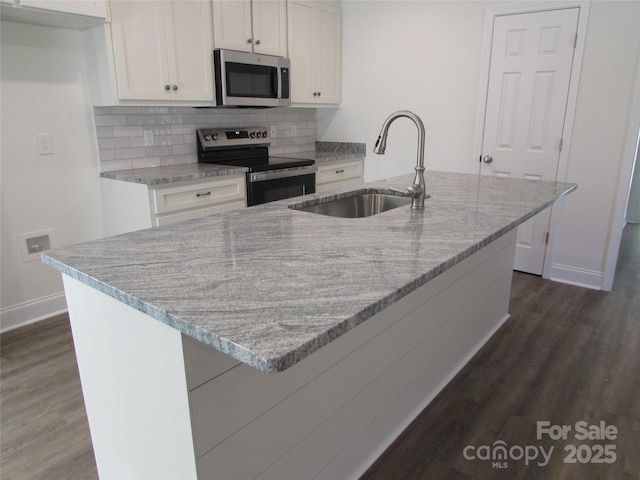 kitchen featuring sink, stainless steel appliances, backsplash, a center island with sink, and white cabinets