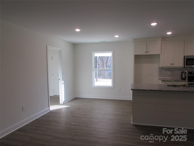 kitchen featuring white cabinetry, sink, dark hardwood / wood-style floors, dark stone countertops, and decorative backsplash