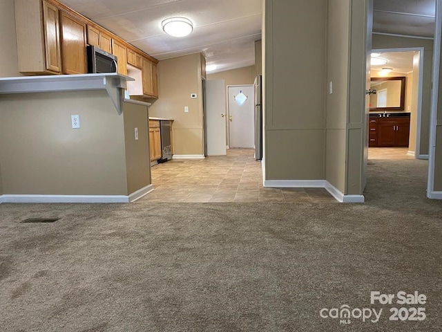 kitchen featuring light carpet, appliances with stainless steel finishes, and lofted ceiling