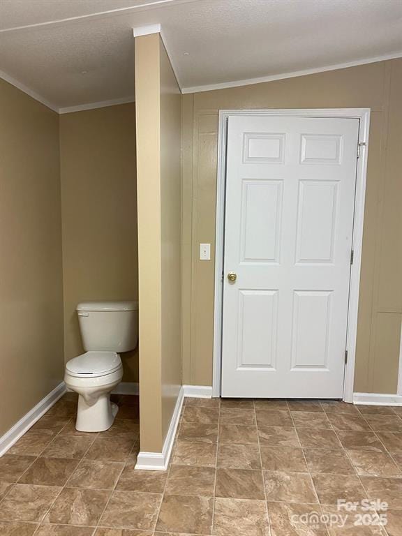 bathroom with lofted ceiling, toilet, and ornamental molding