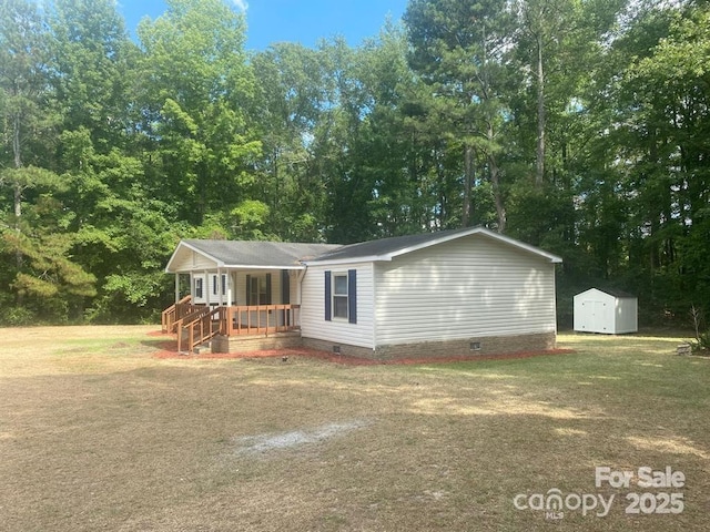 manufactured / mobile home with covered porch, a storage shed, and a front yard