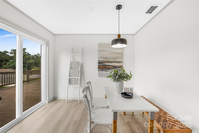 dining area with crown molding and light hardwood / wood-style flooring