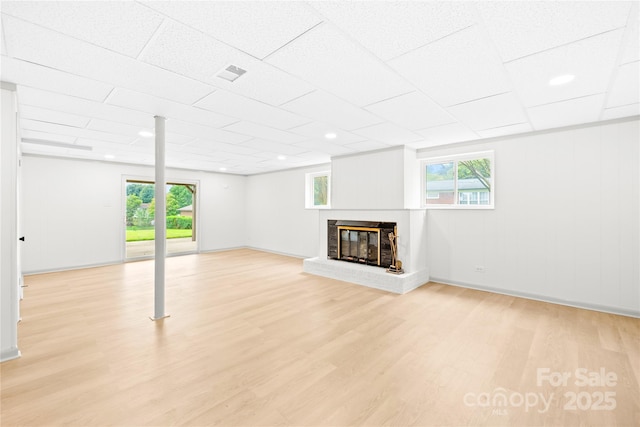 basement with plenty of natural light, a fireplace, and light hardwood / wood-style flooring