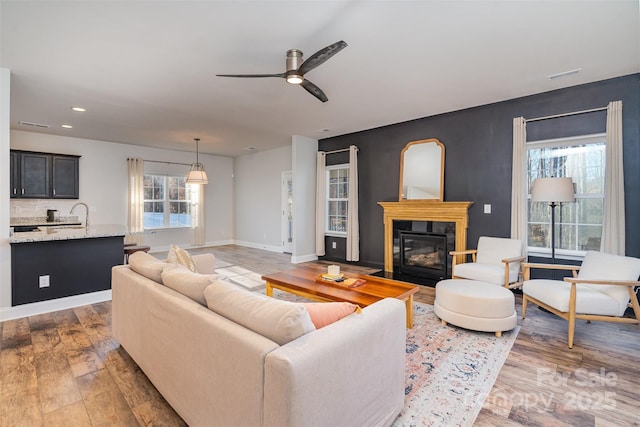 living room featuring ceiling fan, sink, dark wood-type flooring, and a wealth of natural light