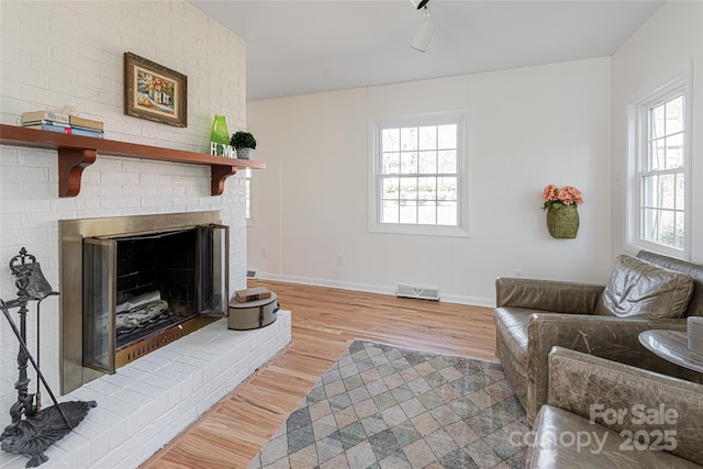 living room with a brick fireplace and light hardwood / wood-style floors