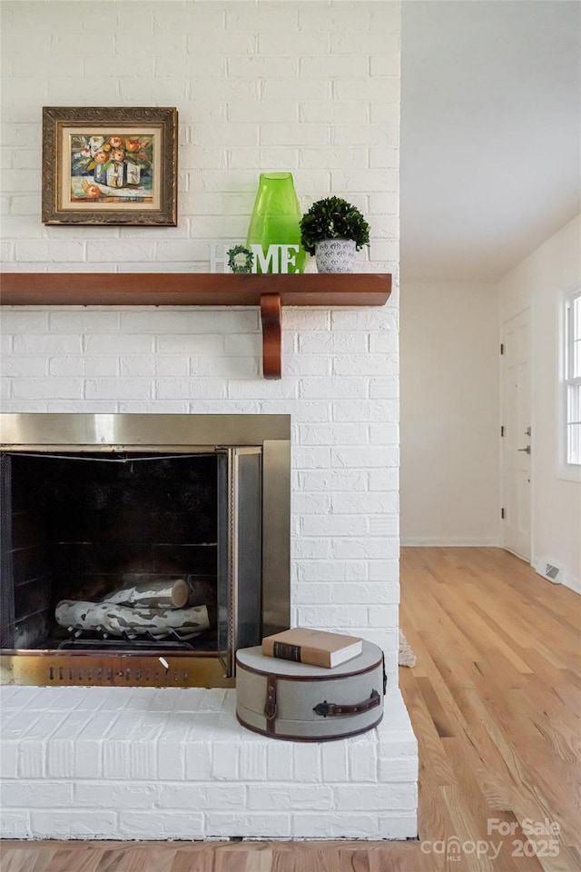 interior details featuring hardwood / wood-style flooring and a brick fireplace