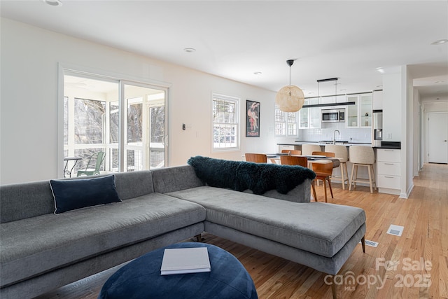 living room with sink and light wood-type flooring