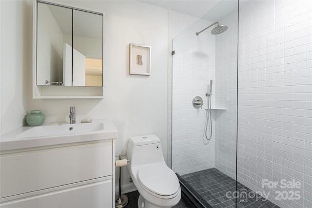 bathroom with tiled shower, vanity, and toilet