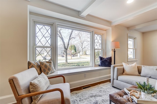 living area with beamed ceiling, a healthy amount of sunlight, and hardwood / wood-style flooring