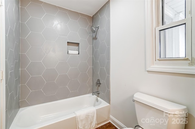 bathroom with tiled shower / bath combo and toilet