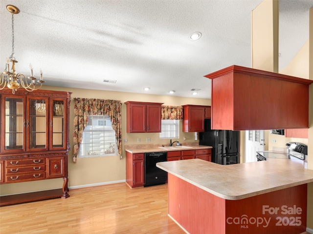 kitchen featuring black appliances, sink, hanging light fixtures, a notable chandelier, and kitchen peninsula