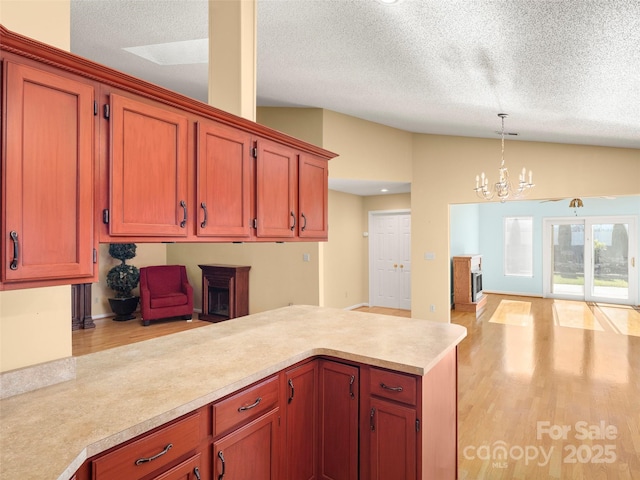 kitchen with a textured ceiling, pendant lighting, light hardwood / wood-style flooring, a notable chandelier, and lofted ceiling