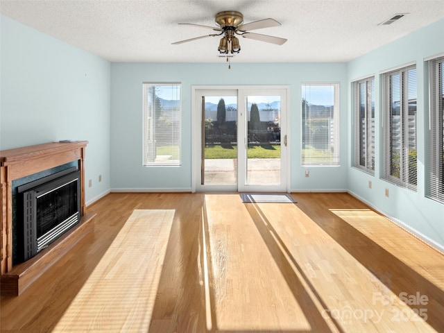 unfurnished living room with a textured ceiling, light wood-type flooring, and a wealth of natural light