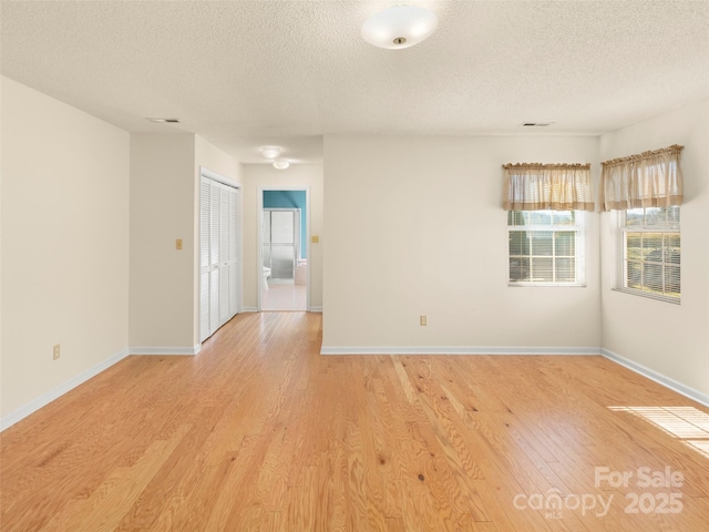 spare room featuring light wood-type flooring and a textured ceiling