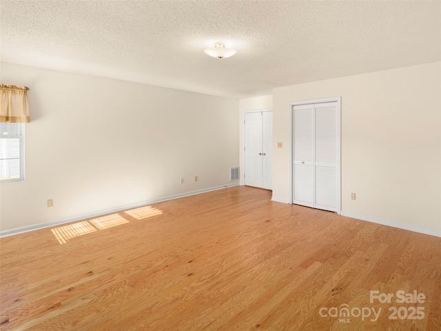 empty room with a textured ceiling and light wood-type flooring