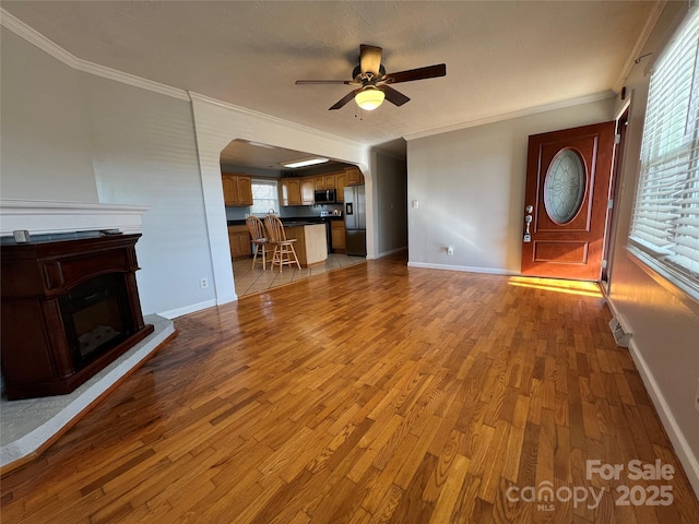 unfurnished living room with hardwood / wood-style flooring, ceiling fan, and crown molding