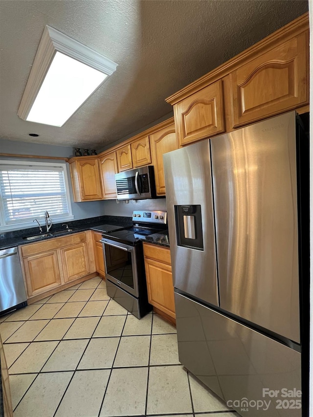 kitchen featuring sink, light tile patterned floors, stainless steel appliances, and a textured ceiling