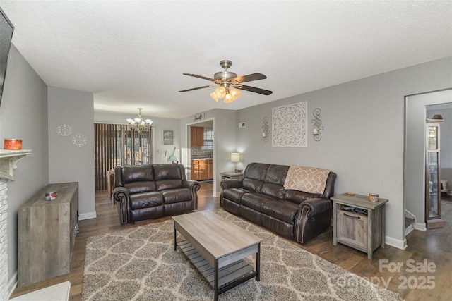 living room with a textured ceiling, ceiling fan with notable chandelier, and dark wood-type flooring