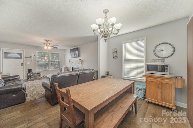 dining space featuring a textured ceiling, ceiling fan with notable chandelier, plenty of natural light, and dark wood-type flooring