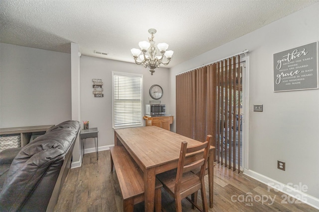 dining space featuring a notable chandelier, dark hardwood / wood-style flooring, and a textured ceiling