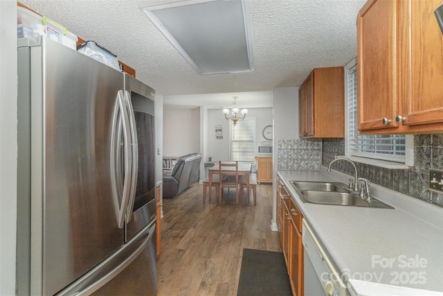 kitchen featuring backsplash, sink, hardwood / wood-style flooring, a textured ceiling, and appliances with stainless steel finishes