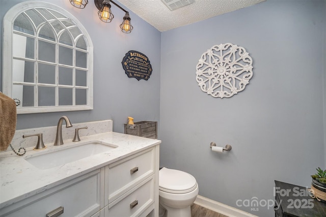 bathroom with vanity, hardwood / wood-style floors, a textured ceiling, and toilet