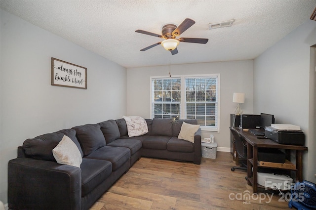 living room with ceiling fan, hardwood / wood-style floors, and a textured ceiling